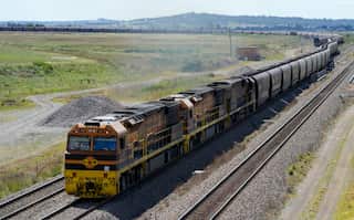 A train covered in black soot travels through the countryside.