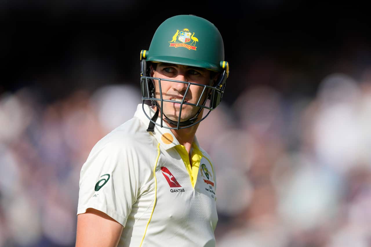 Pat Cummins wearing a cricketers helmet looking to the side. 