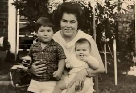 A black and white photo of a woman with two children, the girl a baby