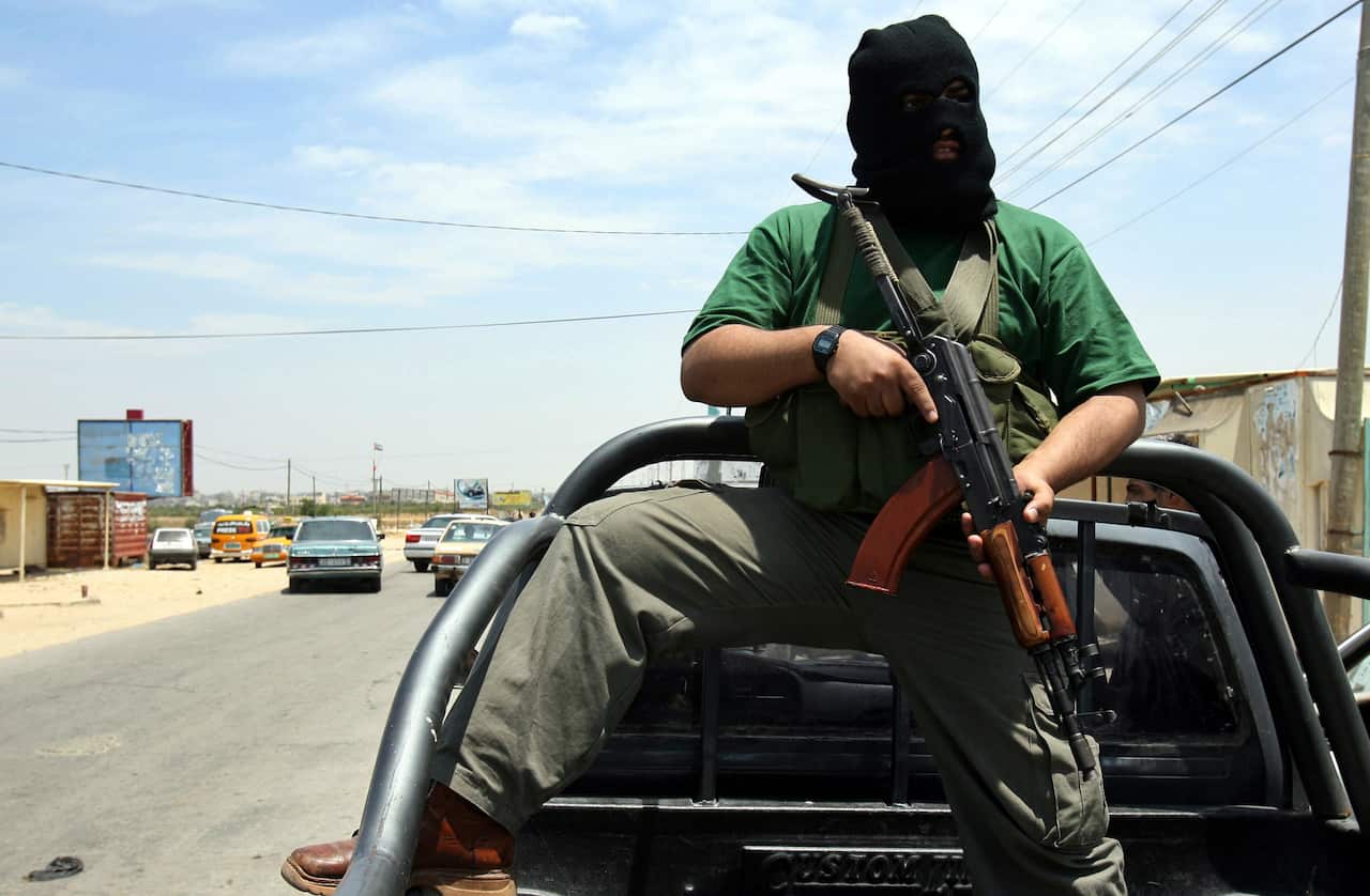 A Palestinian Hamas militant stands in the back of a pickup truck