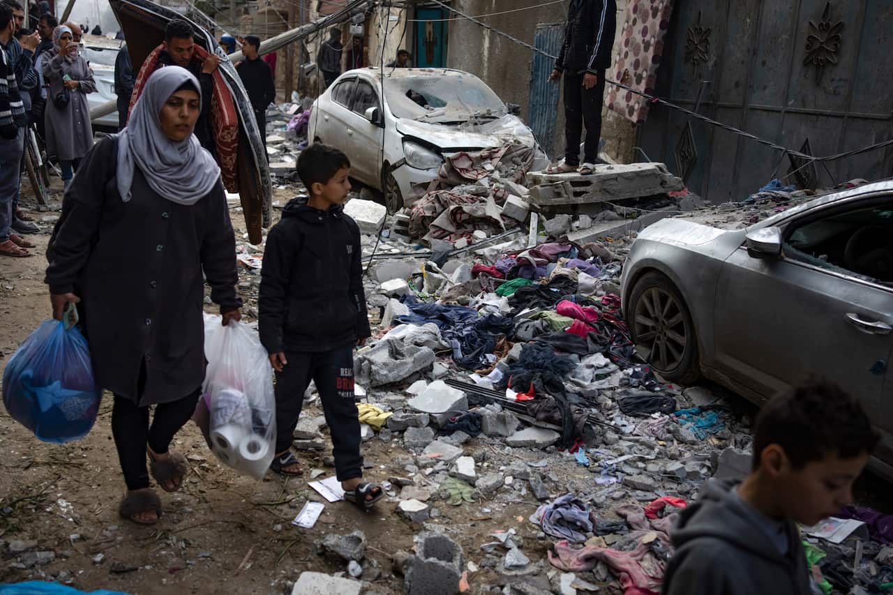 A woman and her child walk past rubble.