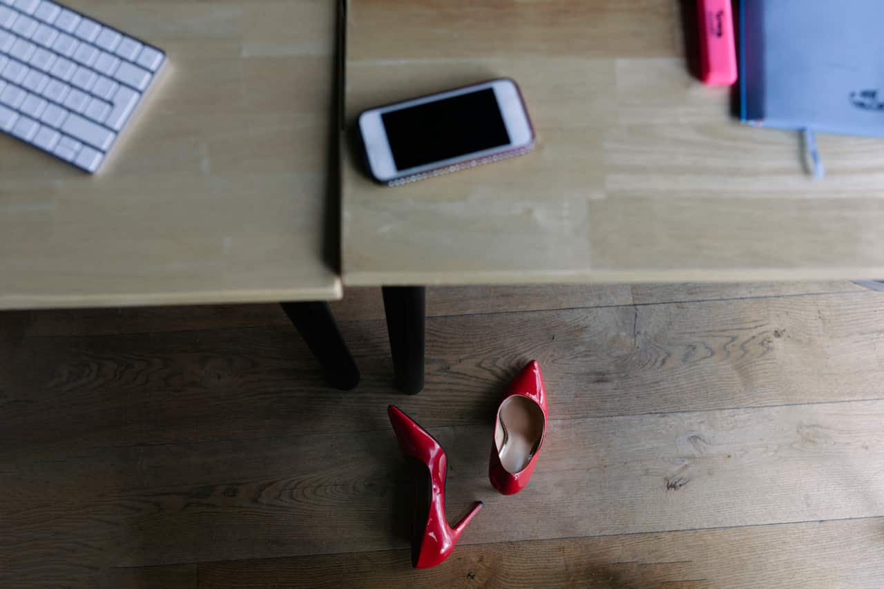 Two red high heel shoes under an office desk.
