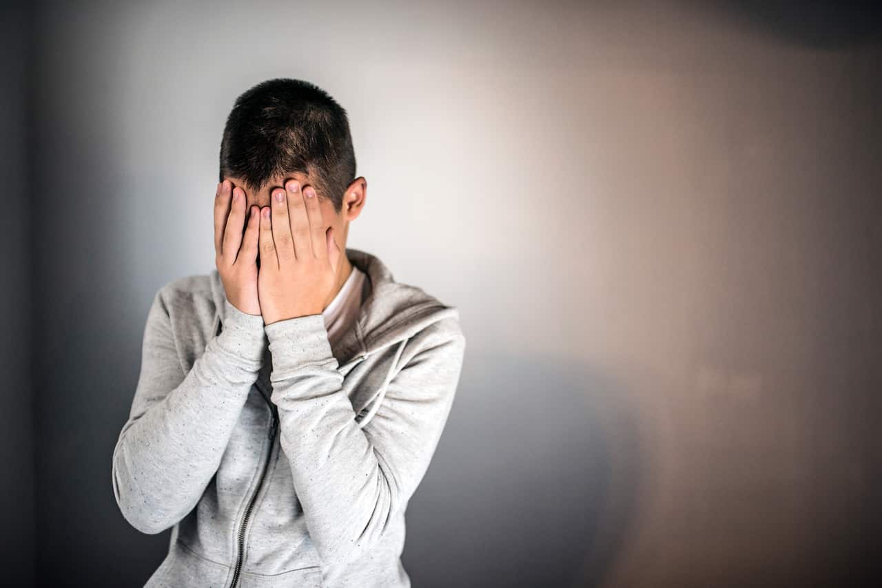 Photo of teenage boy wearing gray jacket against gray background