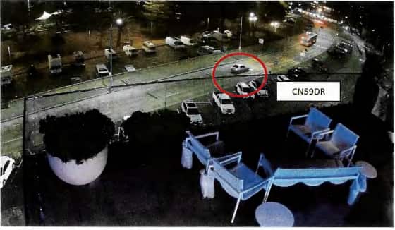 Aerial view of a car driving on a road at night. The car is circled in red.