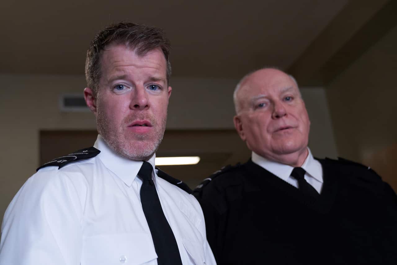 Two prison guards look down at the camera