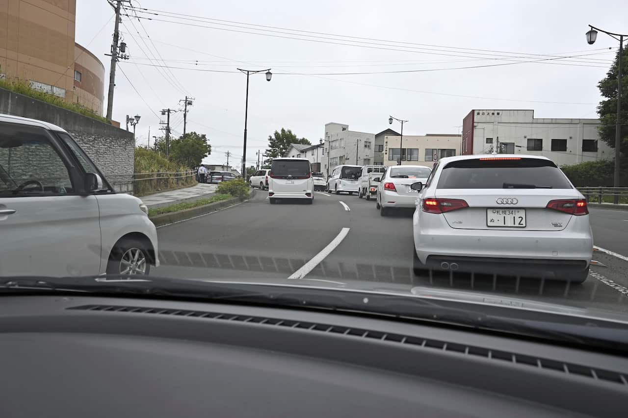 Two rows of cars driving on a road.