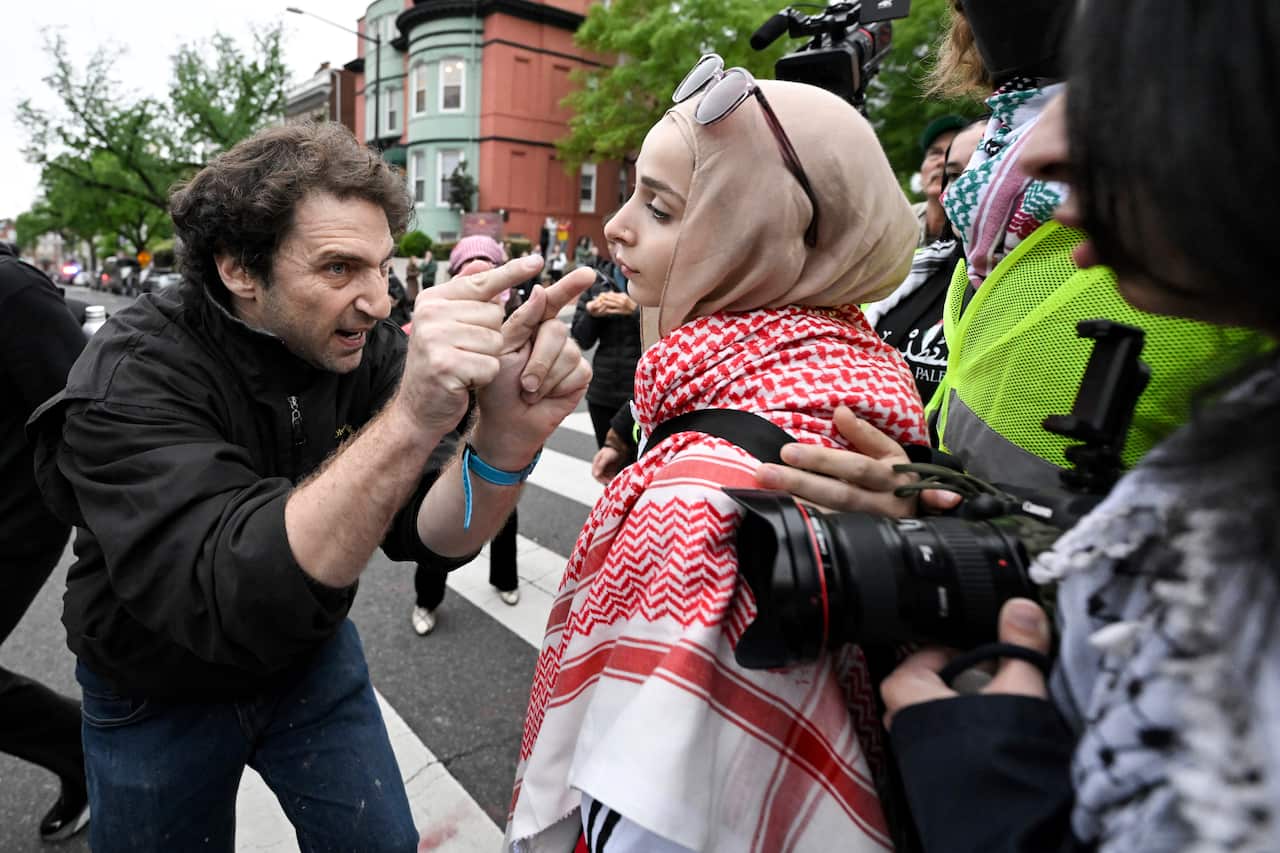 A man pointing fingers at a woman in a hijab and red and white keffiyeh scarf.