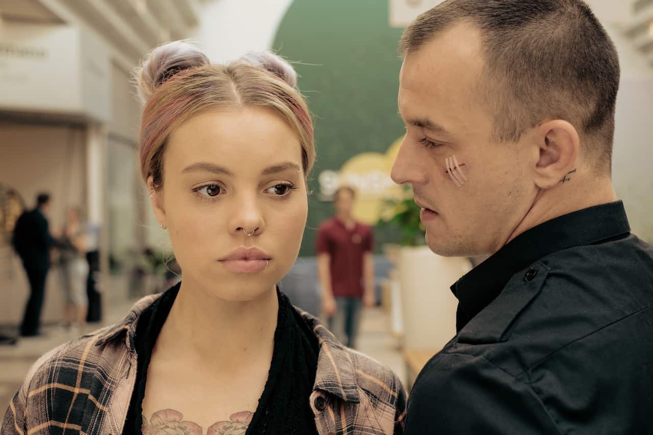 Actors Lea Zoë Voss and Paul Wollin standing next to each other in a mall in German series Breaking Point. Paul has a scar under his left eye.