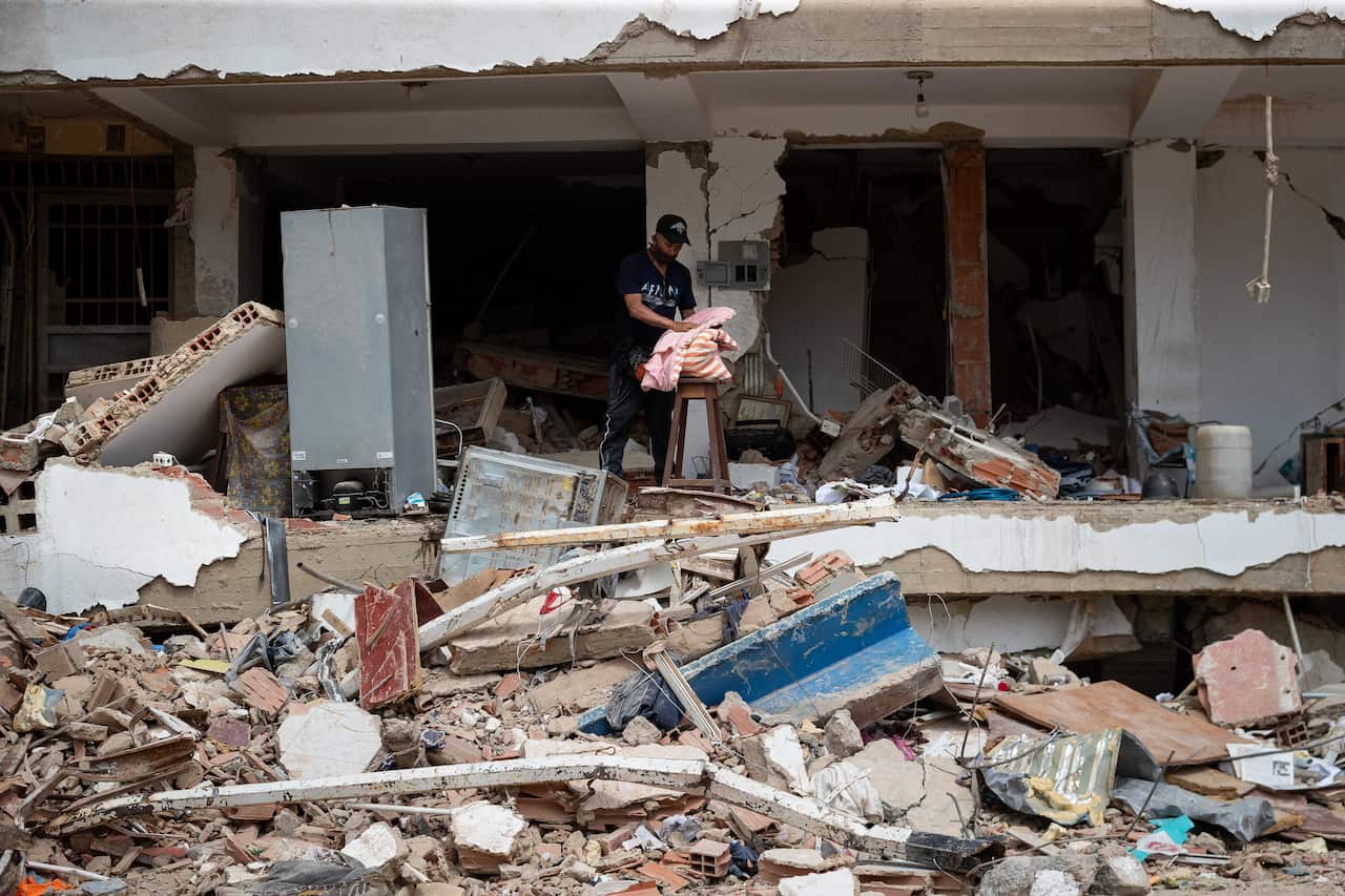 A man collects leftovers as he stands amid the rubble of a building destroyed by earthquakes.
