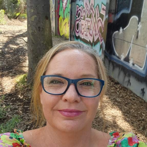 A selfie of a middle-aged woman in glasses smiling at the camera.