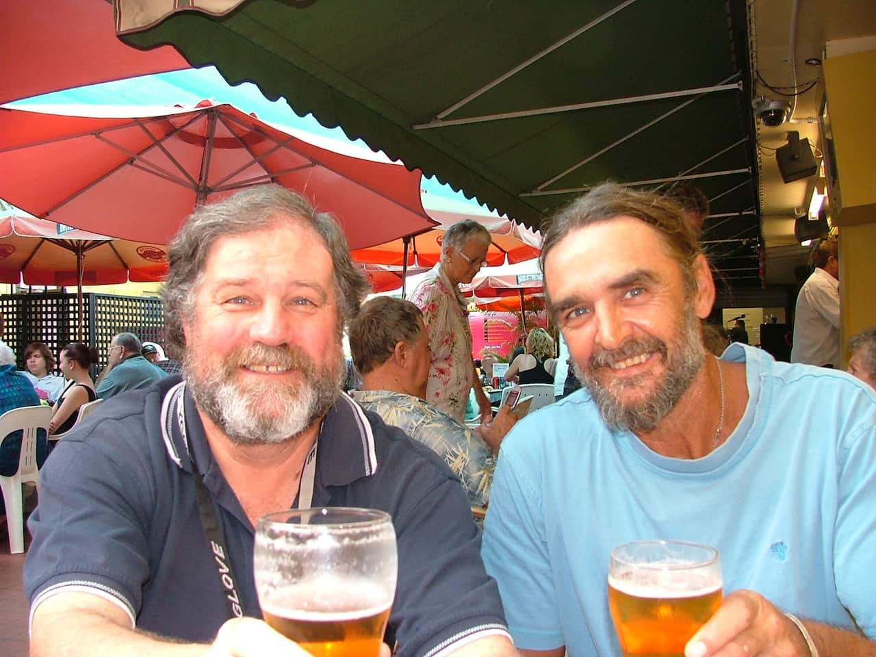 Two men smile as they drink beer.