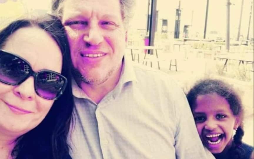 A man, woman and young girl smiling at camera.