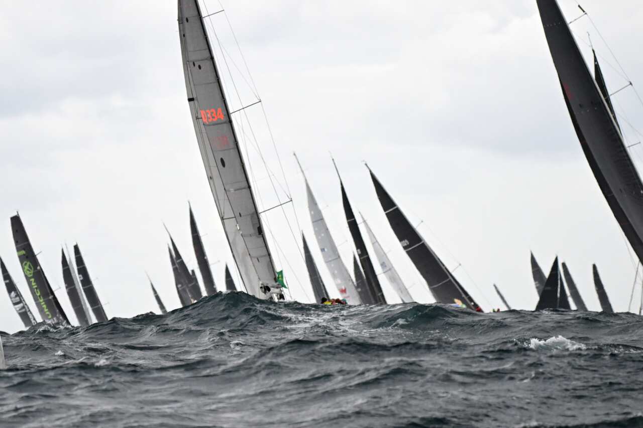 The sails of boats visible above choppy, dark seas.