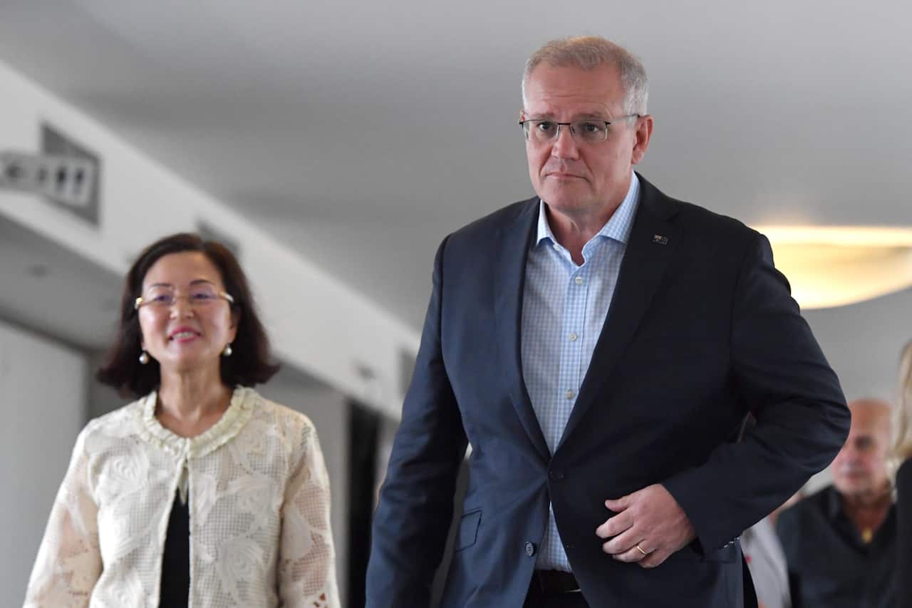 Gladys Liu in white coat walks next to Scott Morrison