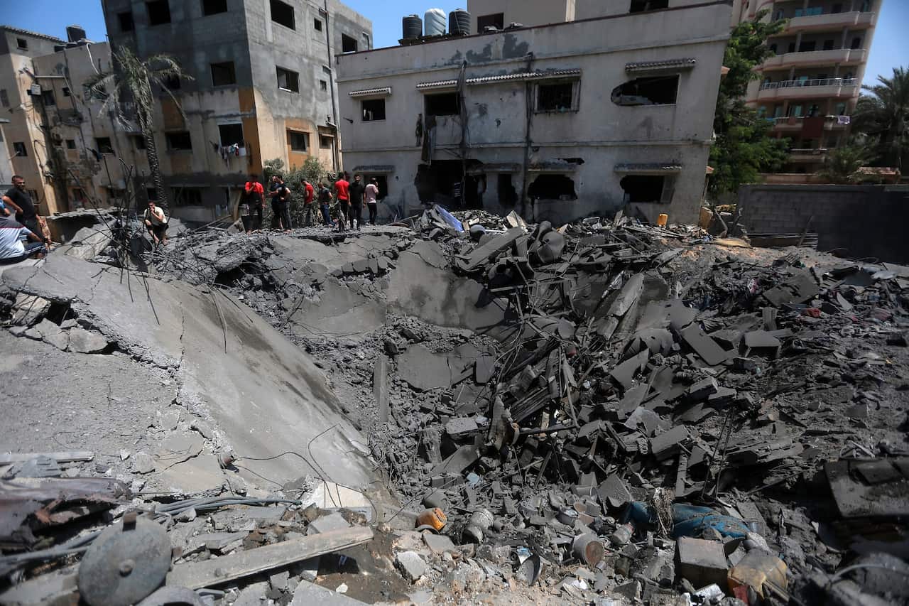 People inspect the rubble of a residential building destroyed by an Israeli airstrike on 6 August 2022 in Gaza City, Gaza.