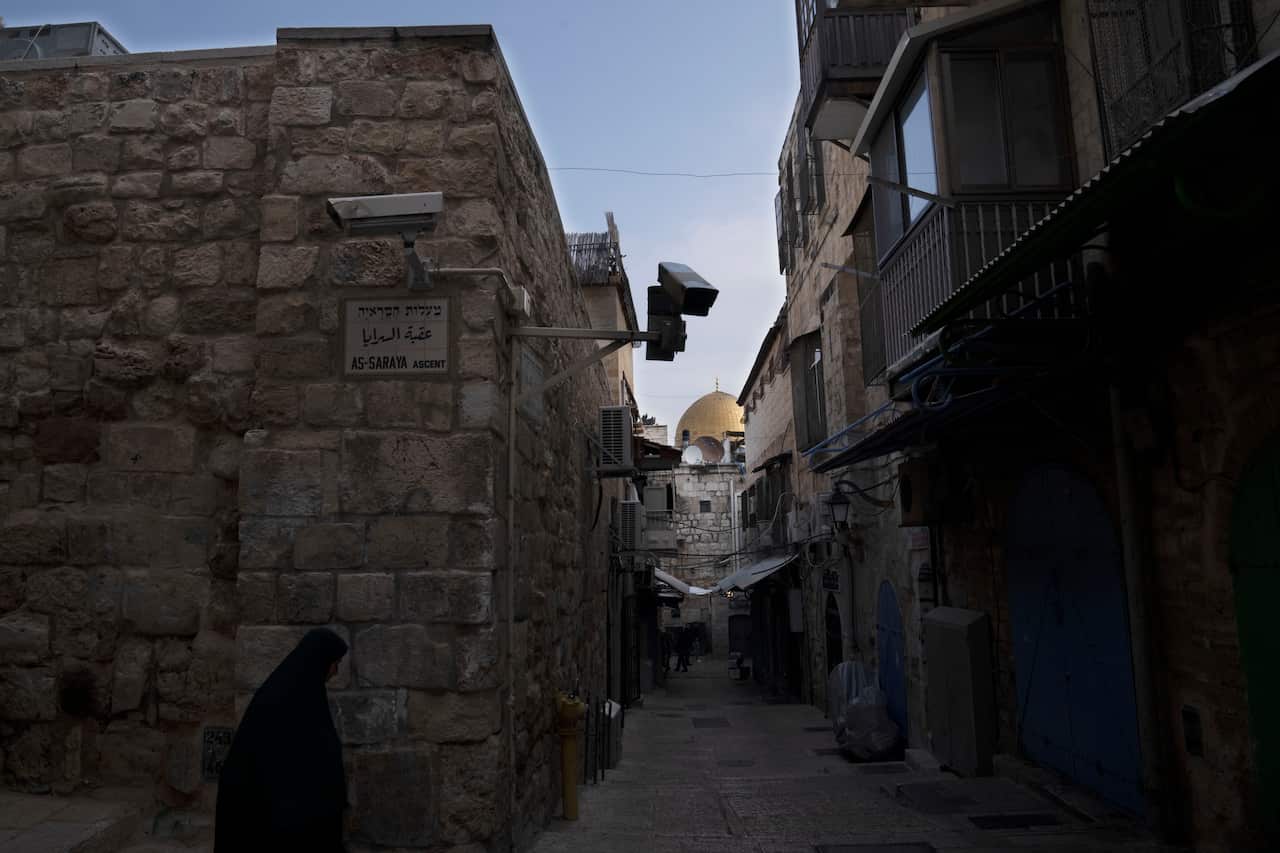 A woman walks through a quiet street inside the walled city of Jerusalem.