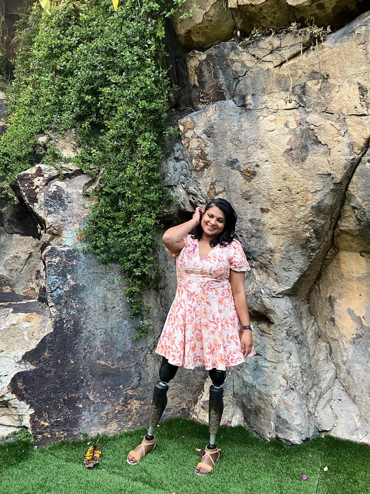 Woman posing for a photo in front of a rock formation. 