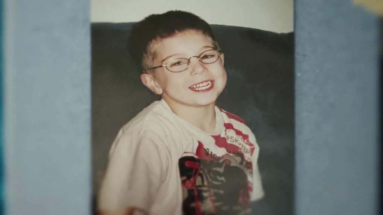 A young child wearing glasses smiles.