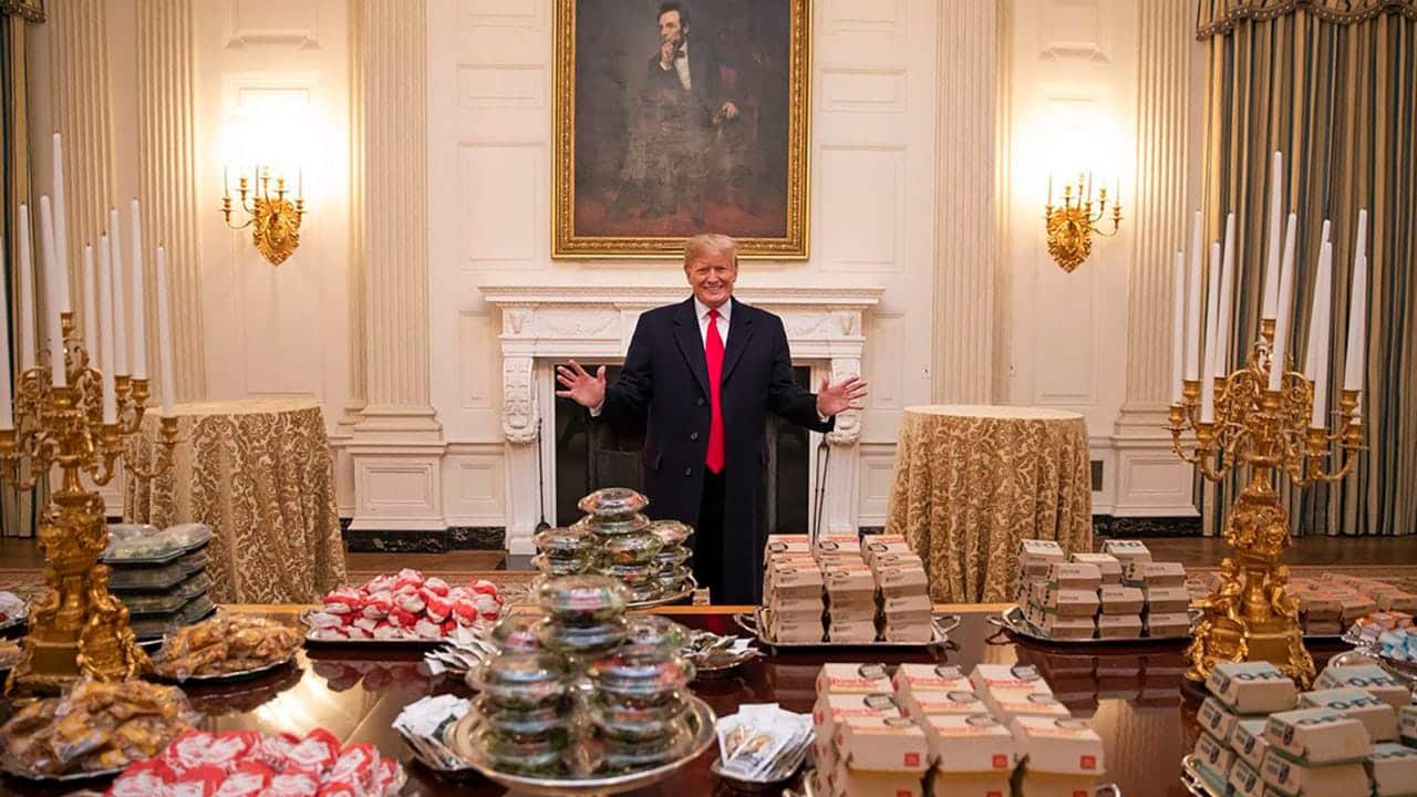 Donald Trump in the White House, behind a table full of McDonald's items.