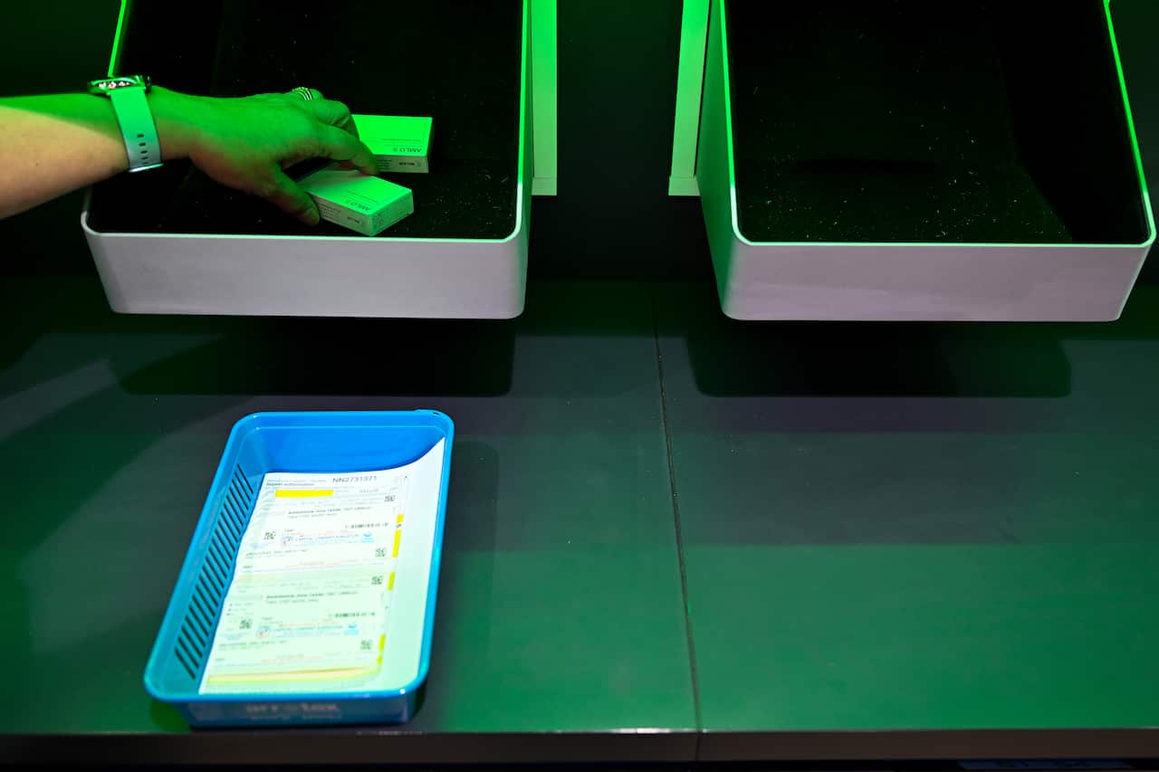 Packaged medication being dispensed into a basket.