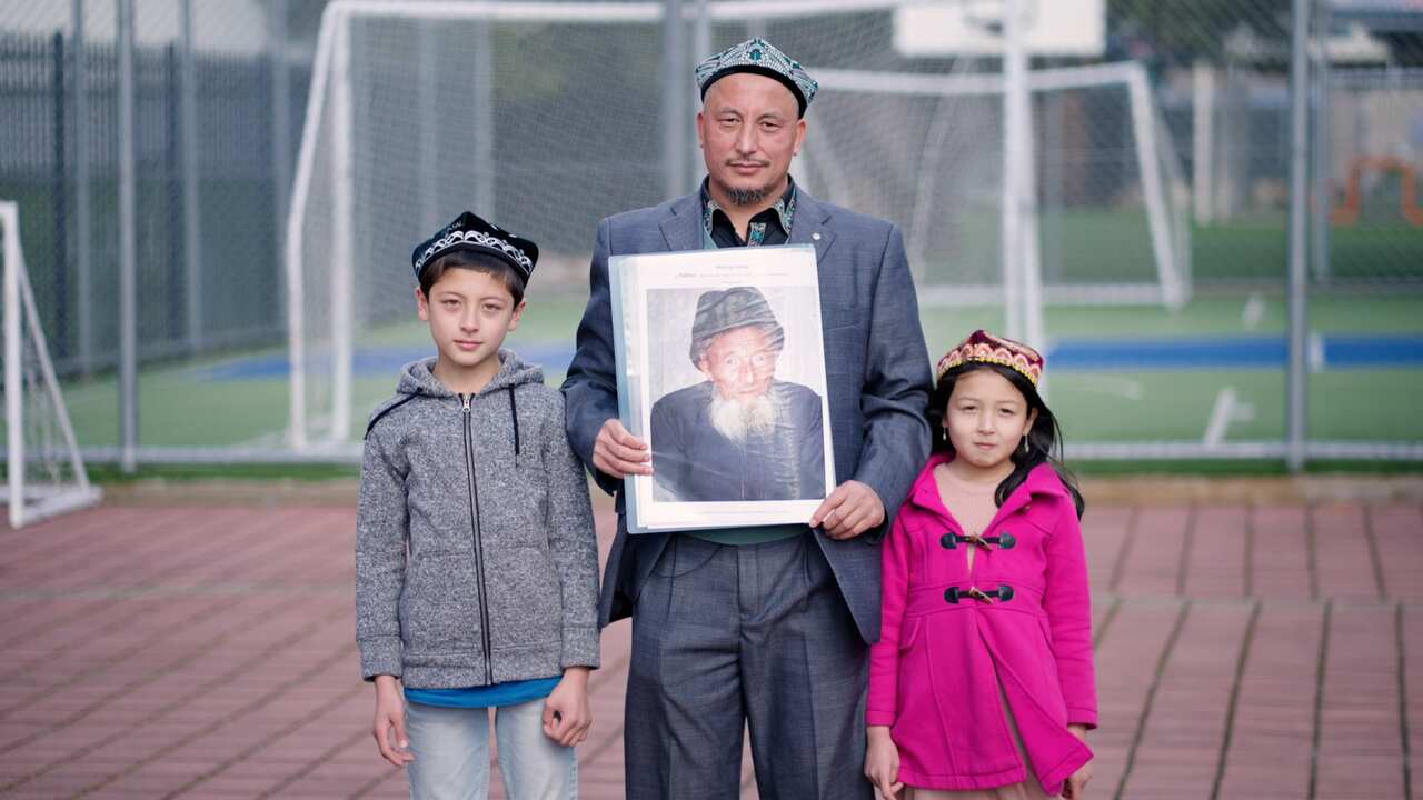 A man holds a photograph with two children by his side.