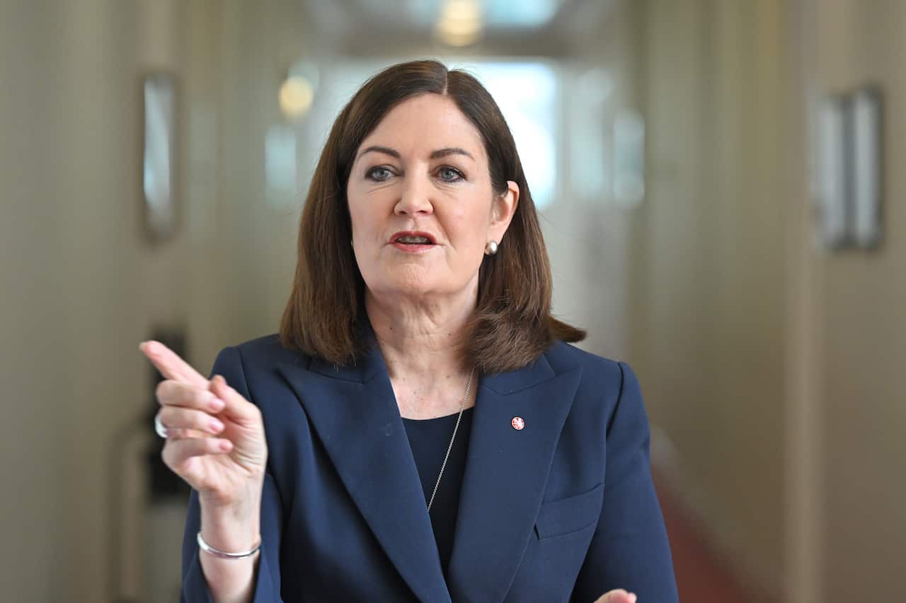 A woman in a suit pointing her finger in a corridor