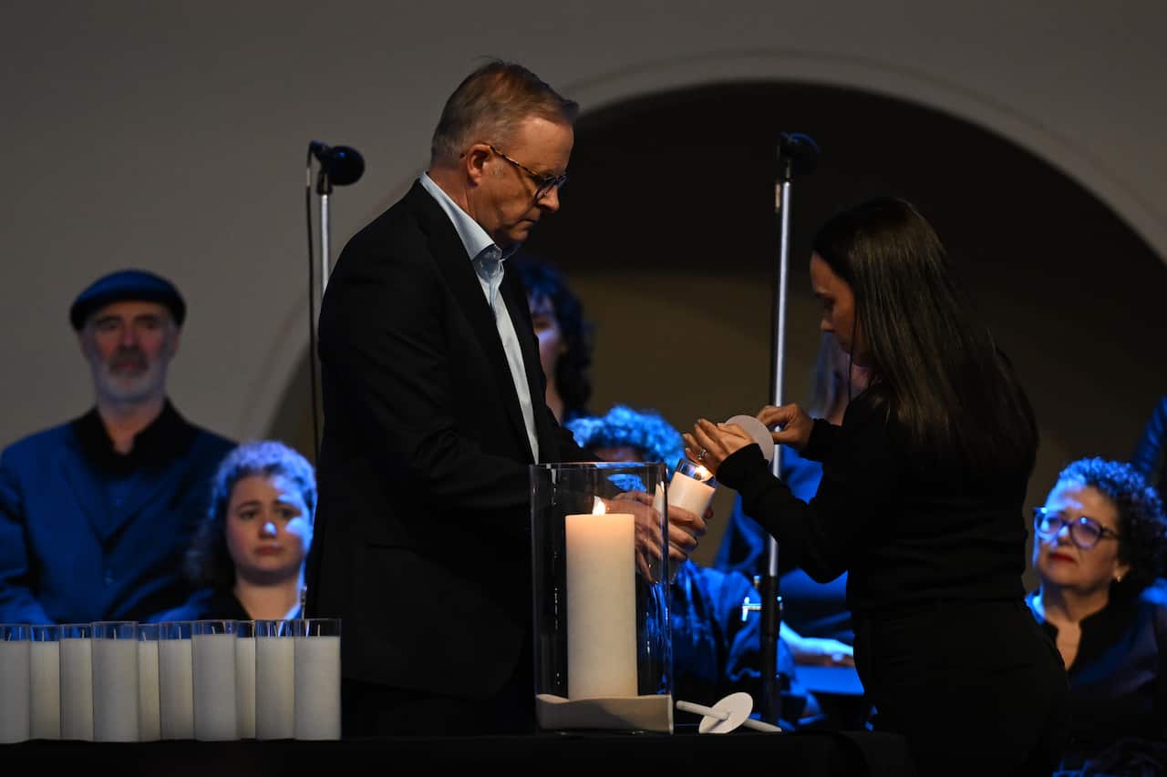 Prime Minister Anthony Albanese lights a candle.