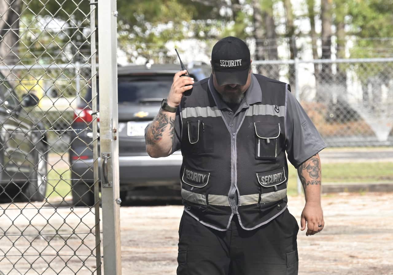 A security guard holding a radio up to his ear.