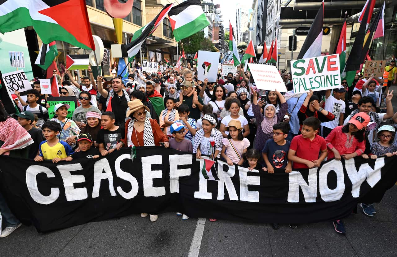 People at a rally hold a banner that reads "ceasefire now"