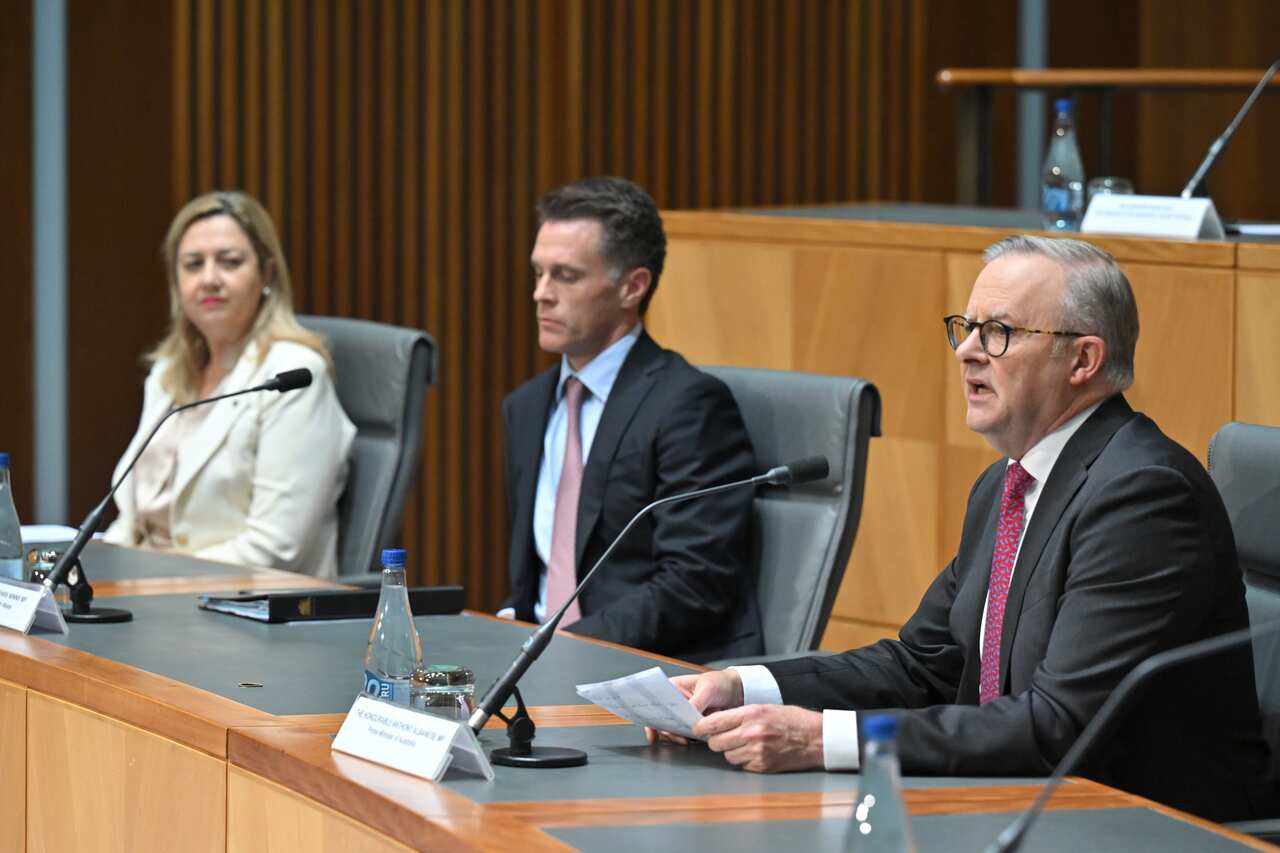 A woman and two men sit in a row