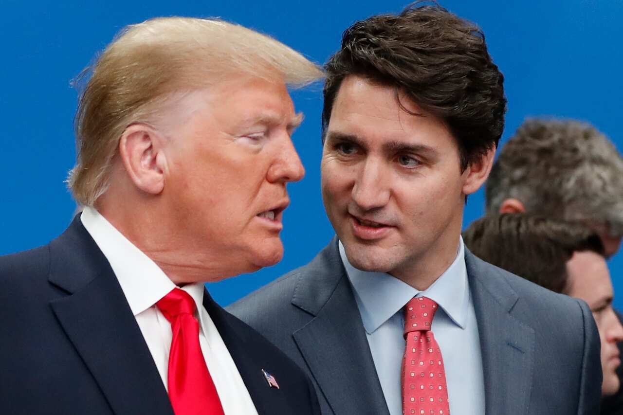Donald Trump and Justin Trudeau speaking to each other in front of a blue background.
