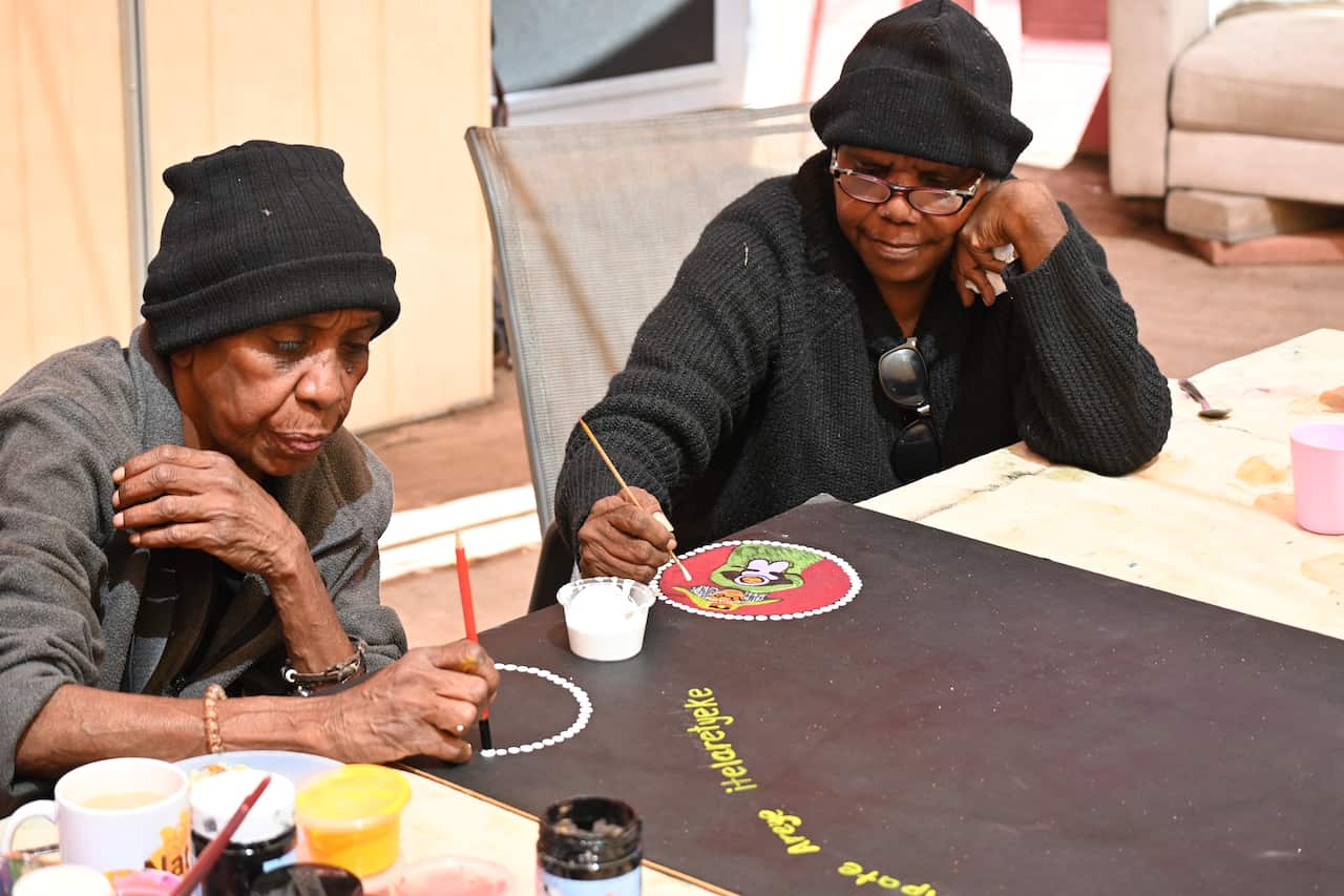 Two women are pictured painting. 