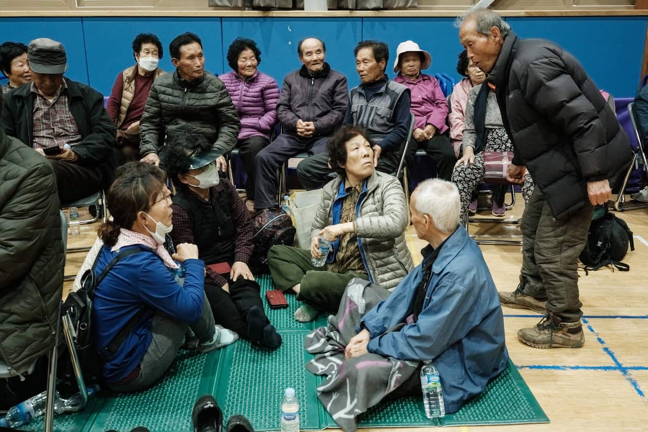 People sitting on the floor of an evacuation site.
