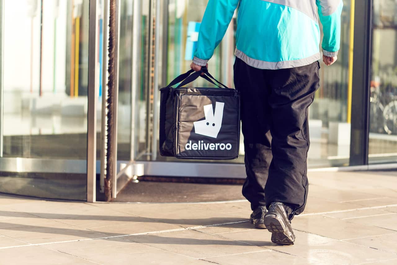 A food delivery worker carrying a bag that has "Deliveroo" written on it.