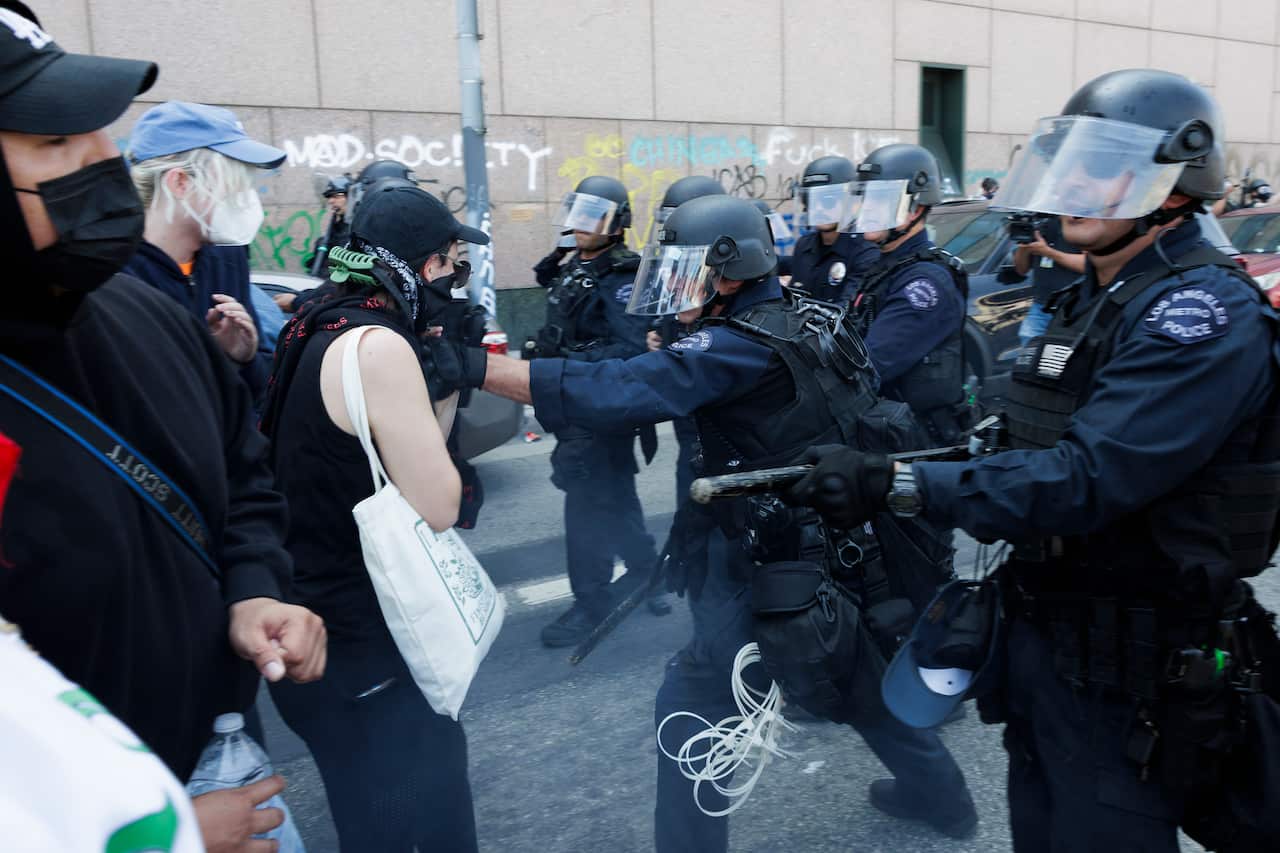 Police clashing with a group of protesters on a street.