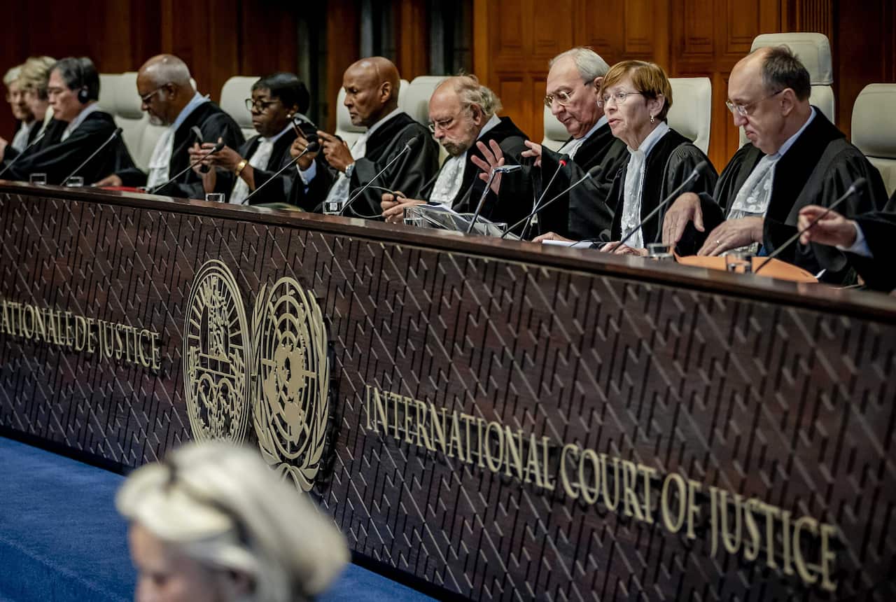 A group of pepole in black robes sitting at an International Court of Justice desk.