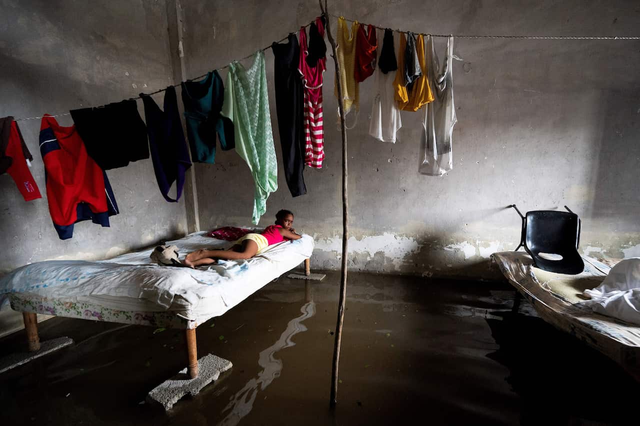 A girl lies on a bed in a room flooded with water.