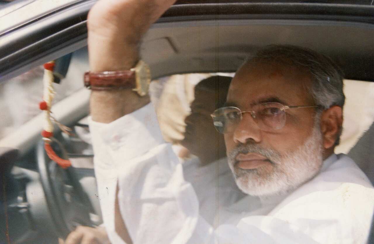 A man sitting in the front passenger seat of a car looking at the camera