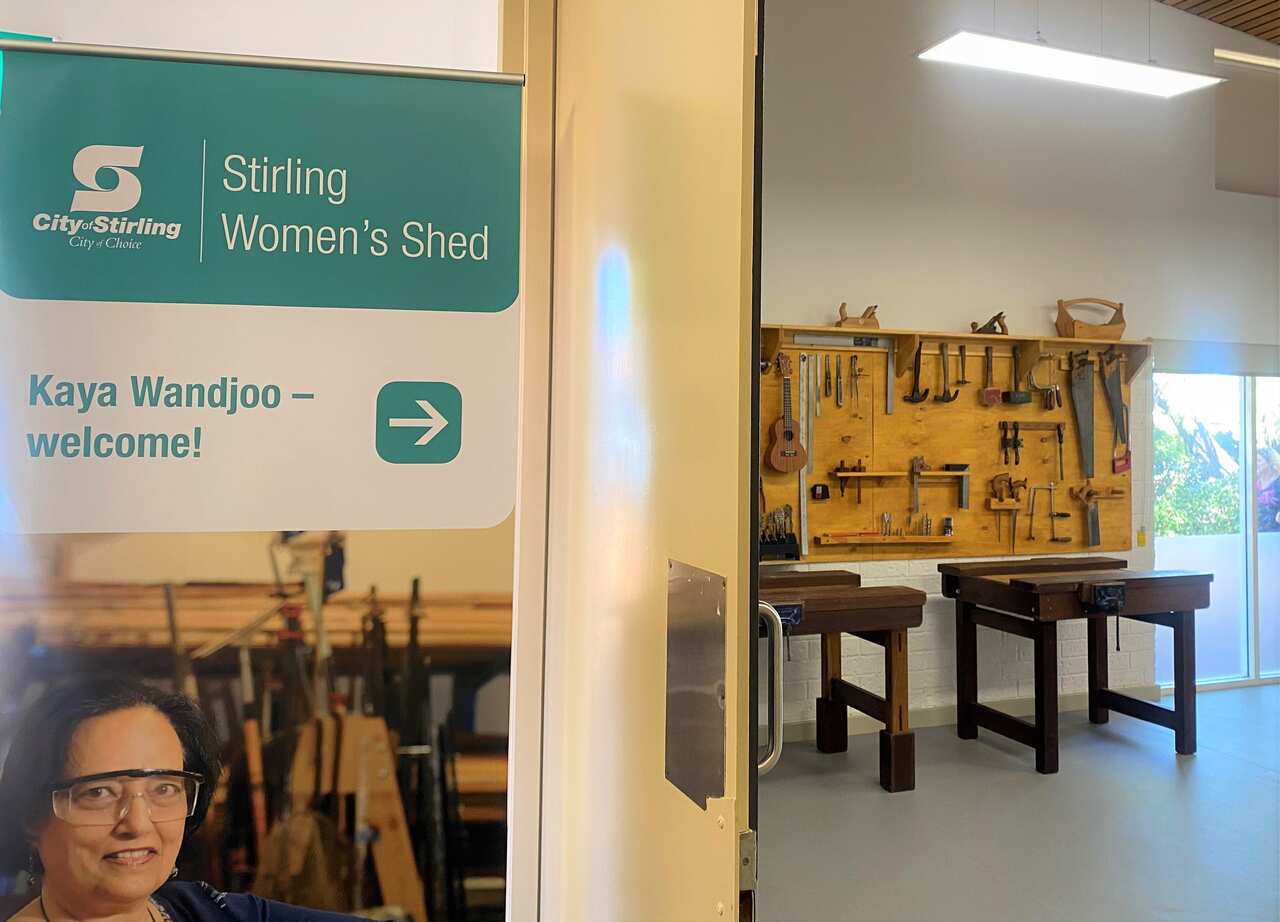 Looking inside the door of the Stirling Women's Shed's temporary home, featuring woodworking tools hanging on a wooden sheet attached to a wall.