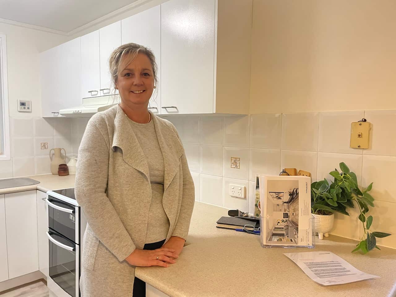 A woman standing next to a bench in a kitchen 