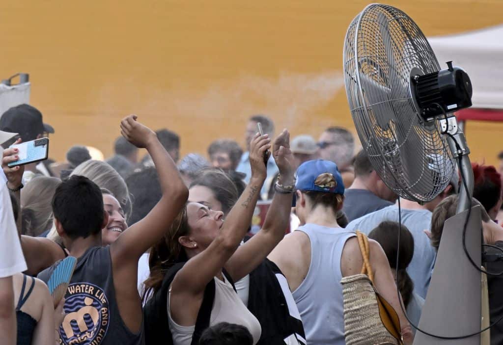 Tourists in Italy huddle around a wire fan trying to cool off.