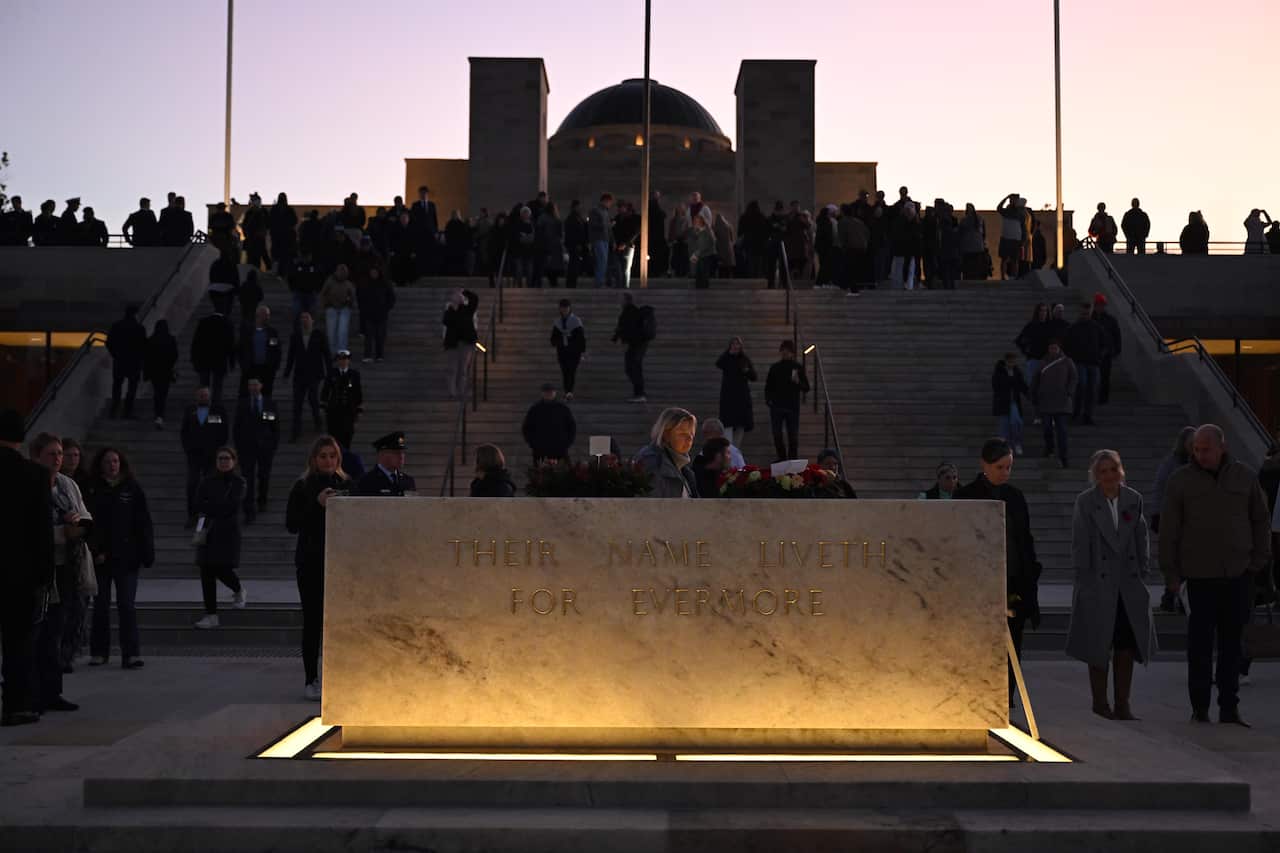 A large group of people on the steps at the Australian War Memorial at dawn.