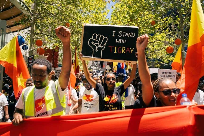 Noha Tsehaye at a rally in Perth, holding a sign reading 'I stand with Tigray'.