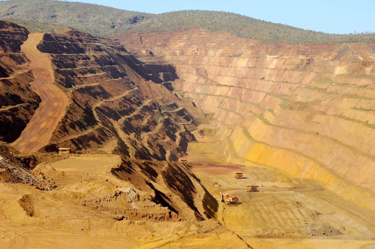 A large open-cut mine with trucks at the bottom of it