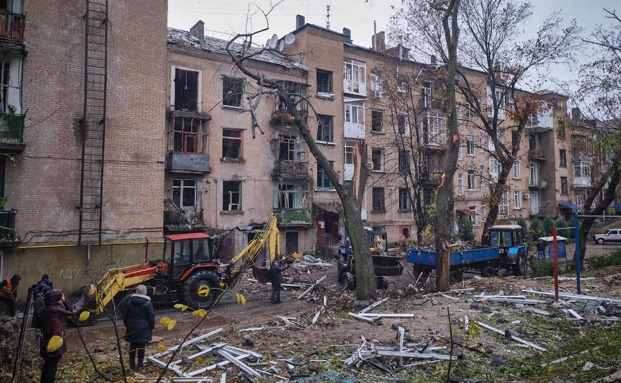 People standing outside a damaged residential building.