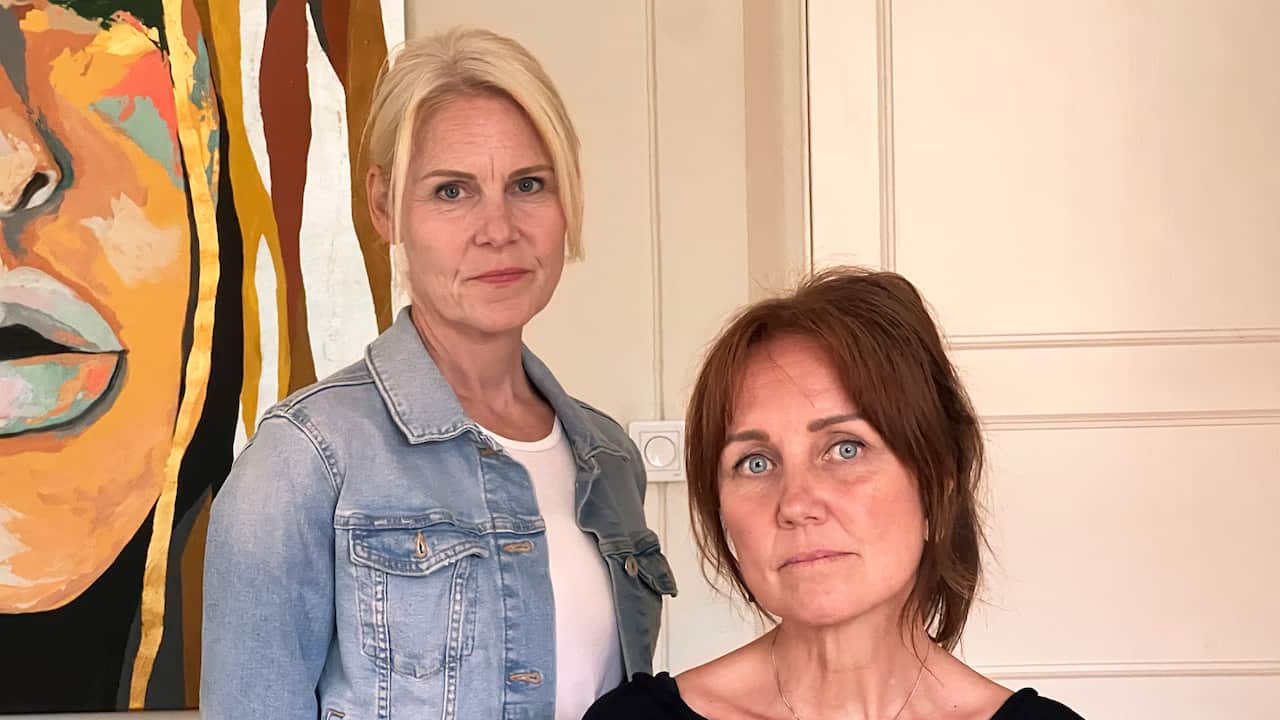 A blonde woman wearing a denim jacket next to a brunette woman in a dark top