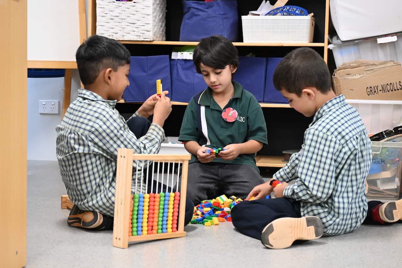 Three children sitting on the floor play with toys