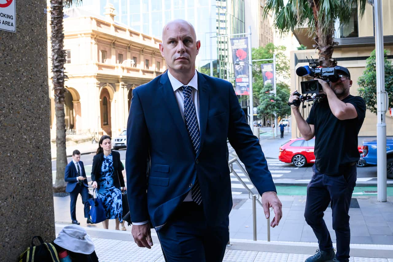 A man wearing a suit arrives at court.