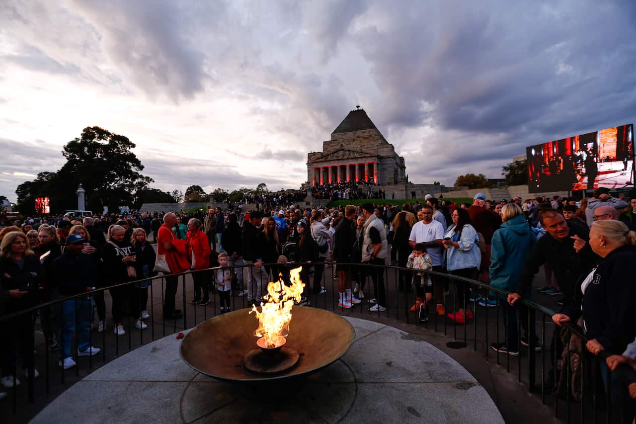 A large group of people standing around an 'eternal flame', a torch that is continuing to burn.