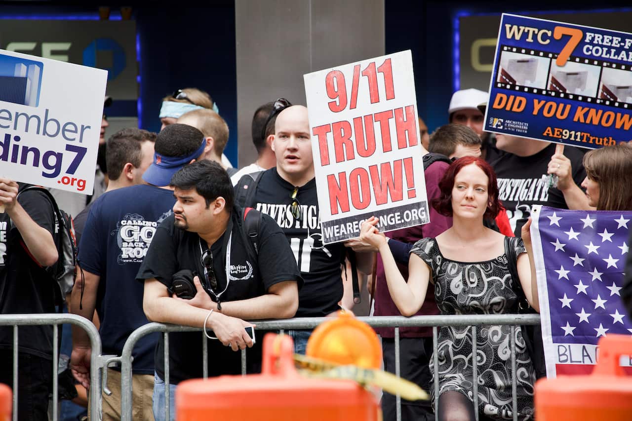 Protesters holding up signs questioning the official 9/11 narrative